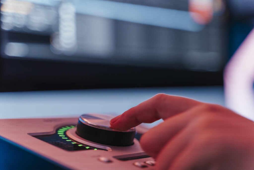 Mano ajustando el control de una tarjeta de sonido profesional en un entorno de estudio musical.