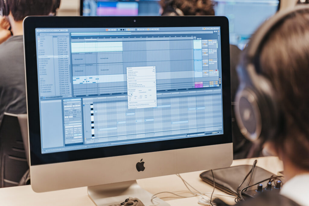Alumne amb auriculars utilitzant Ableton Live en un iMac durant una sessió pràctica del curs de producció musical d’EUMES.